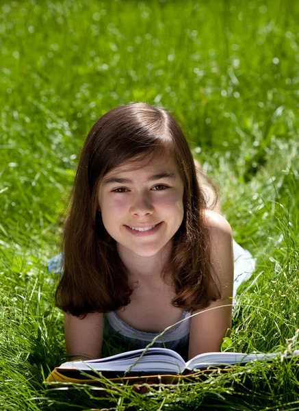 Chica acostada en verde prado lectura libro —  Fotos de Stock