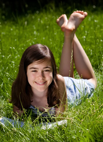 Flickan liggande på gröna ängen läser bok — Stockfoto