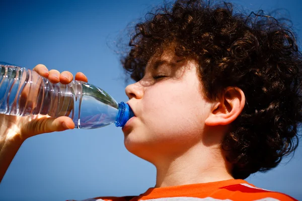 Junge trinkt Wasser gegen blauen Himmel — Stockfoto