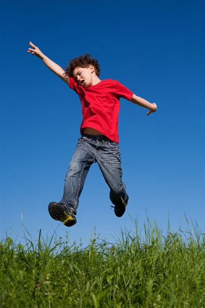 Boy jumping against blue sky — Stock Photo, Image