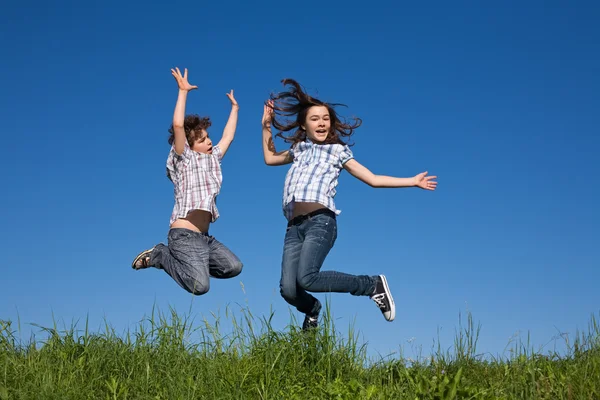 Girl and boy jumping outdoor — Stock Photo, Image