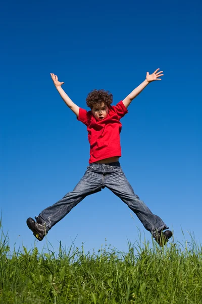 Boy jumping against blue sky — Stock Photo, Image