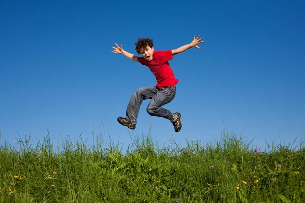 Junge springt gegen blauen Himmel — Stockfoto
