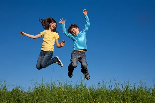 Girl and boy jumping outdoor — Stock Photo, Image