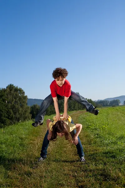 Chica y niño saltando, corriendo al aire libre — Foto de Stock