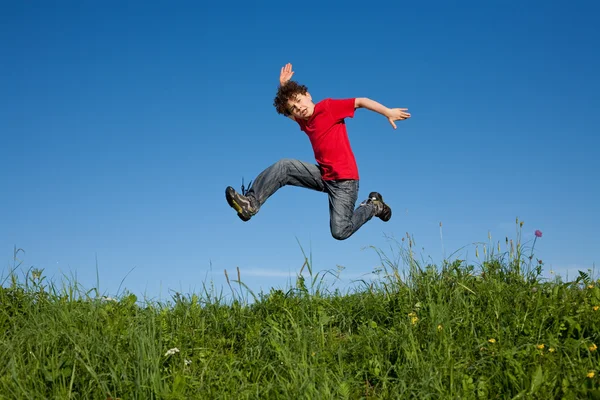 Rapaz a saltar contra o céu azul — Fotografia de Stock