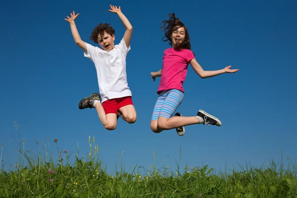 Girl and boy jumping outdoor — Stock Photo, Image