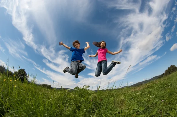 Chica y niño saltando al aire libre — Foto de Stock