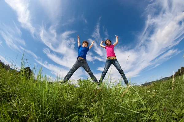Menina e menino pulando ao ar livre — Fotografia de Stock
