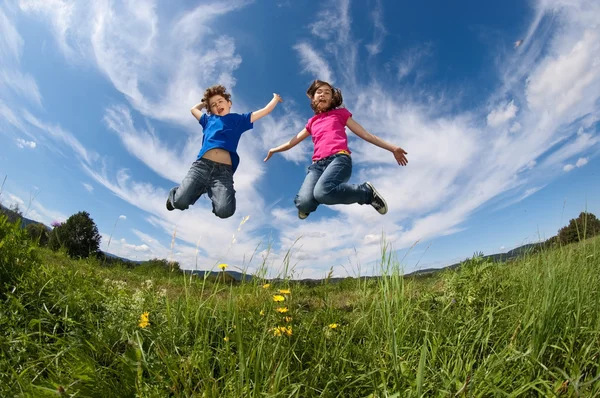 Ragazza e ragazzo saltare all'aperto — Foto Stock