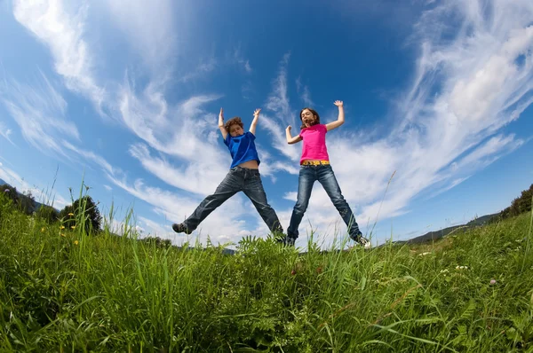 Girl and boy jumping outdoor — Stock Photo, Image