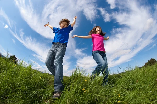 Girl and boy jumping outdoor — Stock Photo, Image