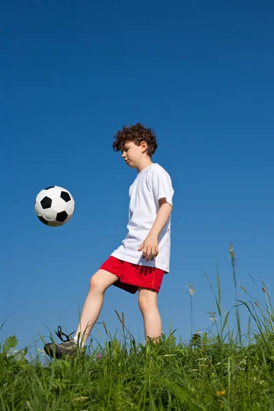 Junge spielt Fußball lizenzfreie Stockfotos