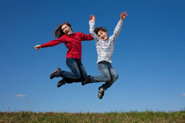 Bambini che saltano contro il cielo blu — Foto Stock