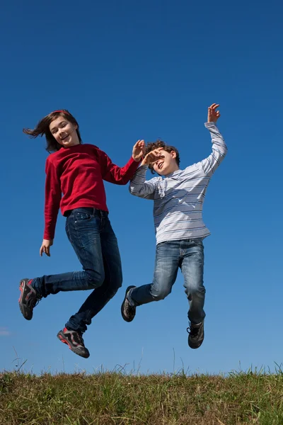 Kids jumping against blue sky — Stock Photo, Image