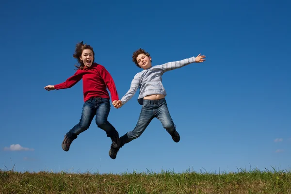 Діти стрибають проти блакитного неба — стокове фото