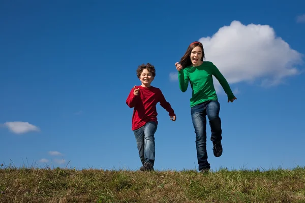Děti skákat proti modré obloze — Stock fotografie