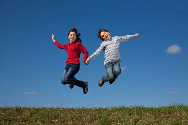 Kids jumping against blue sky — Stock Photo, Image