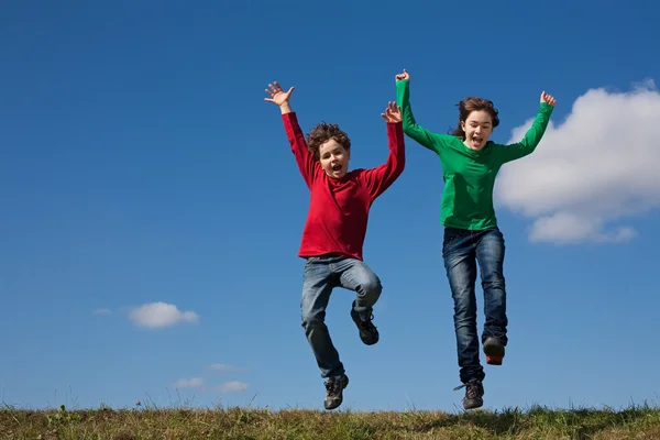 Niños saltando contra el cielo azul —  Fotos de Stock