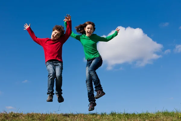 Kinderen springen tegen blauwe hemel — Stockfoto