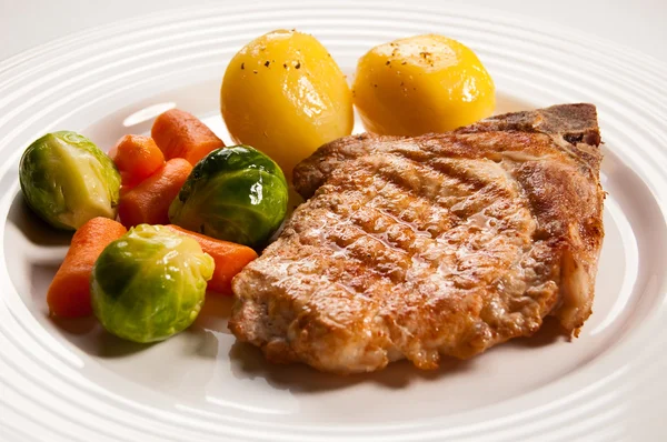 Gegrilde steaks, gebakken aardappelen en groentesalade — Stockfoto