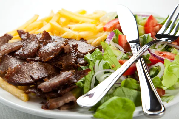 М'ясо на грилі зі смаженою картоплею та овочевим салатом — стокове фото