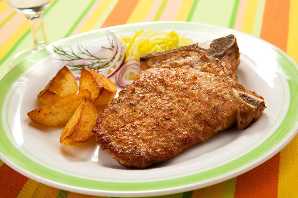 Carne de porco grelhada, batatas fritas e salada de legumes — Fotografia de Stock