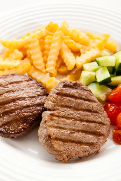 Grilled steaks, chips and vegetables — Stock Photo, Image