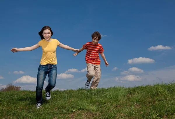 Chica y niño saltando, corriendo al aire libre — Foto de Stock