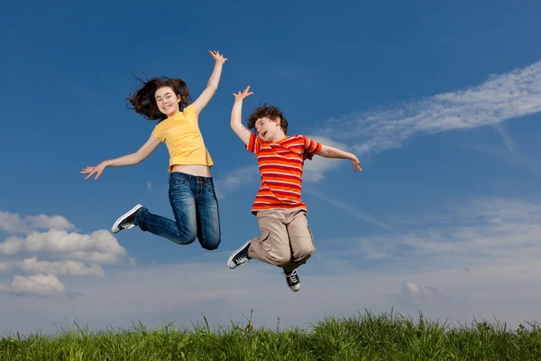 Girl and boy jumping against blue sky Royalty Free Stock Photos
