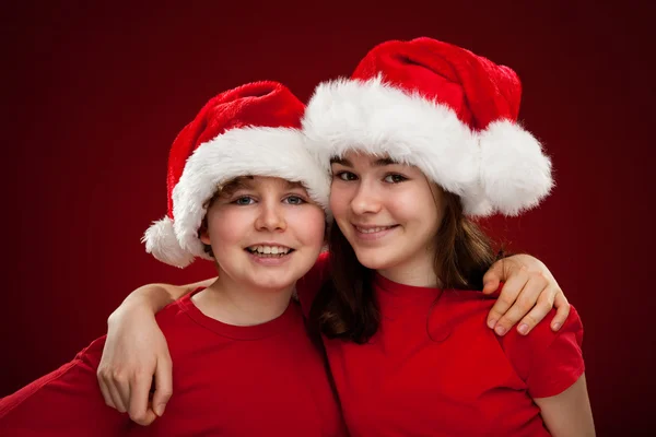 Chlapec a dívka s santa claus klobouky — Stock fotografie