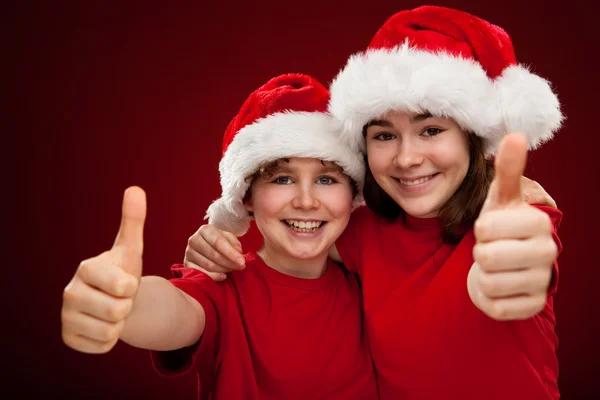 Pojke och flicka med santa claus hattar — Stockfoto