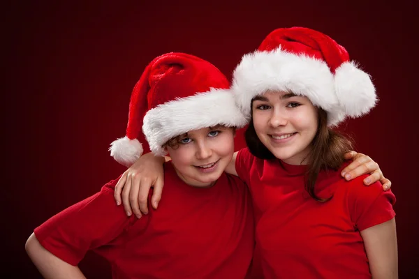 Niño y niña con Santa Claus Sombreros —  Fotos de Stock