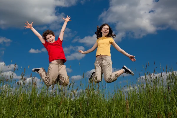 Menina e menino pulando ao ar livre — Fotografia de Stock
