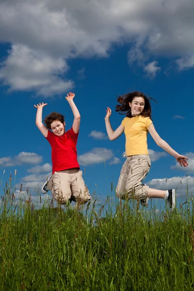 Ragazza e ragazzo saltare all'aperto — Foto Stock