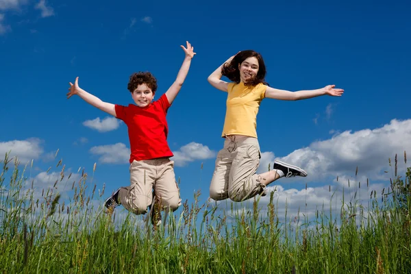 Girl and boy jumping outdoor — Stock Photo, Image