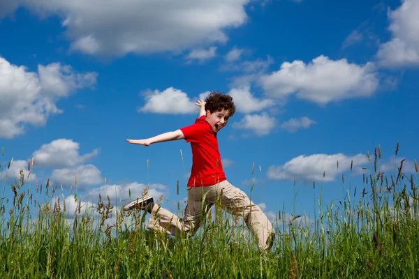 Boy jumping against blue sky — Stock Photo, Image