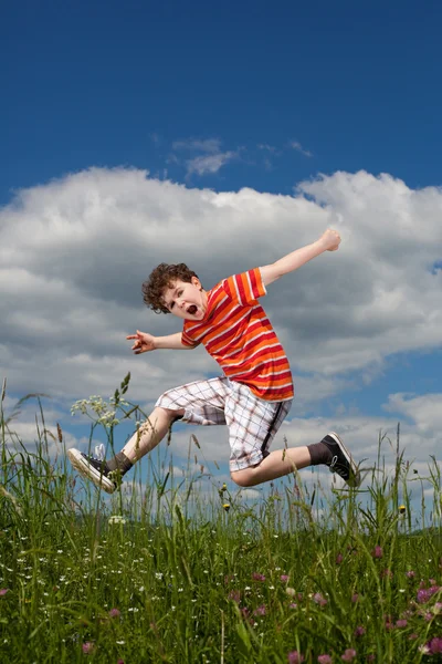 Junge springt gegen blauen Himmel — Stockfoto