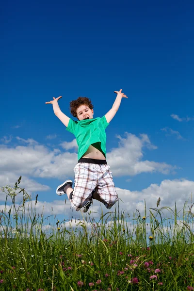 Junge springt gegen blauen Himmel — Stockfoto