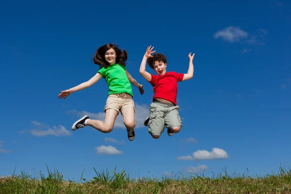 Fille et garçon sautant en plein air — Photo