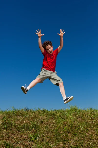 Junge springt gegen blauen Himmel — Stockfoto