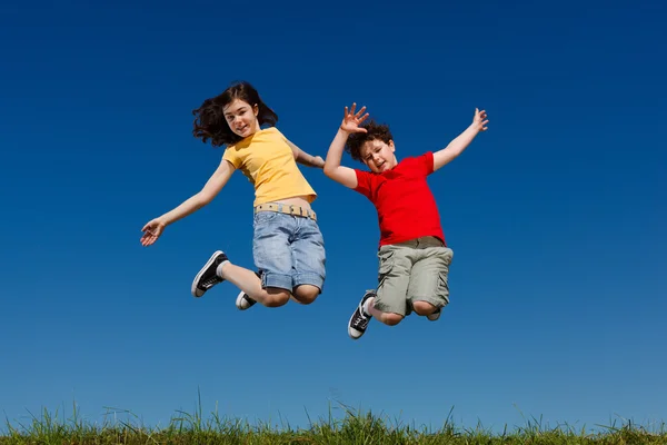 Mädchen und Junge springen im Freien — Stockfoto