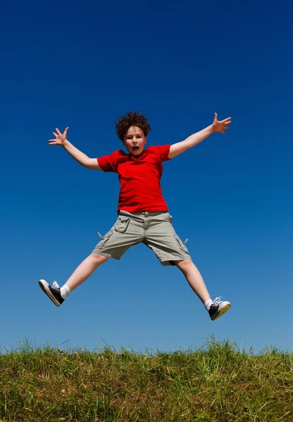 Ragazzo che salta, corre contro il cielo blu — Foto Stock