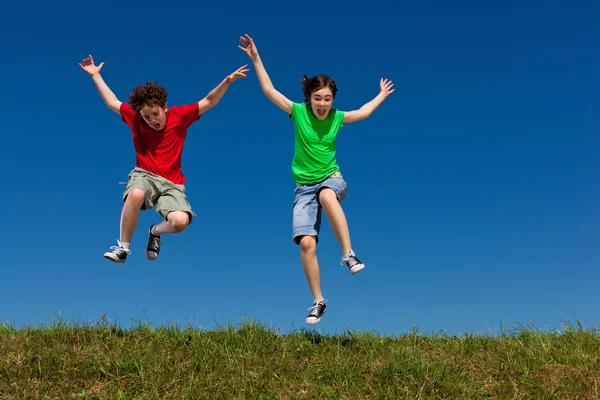 Girl and boy jumping outdoor Stock Image