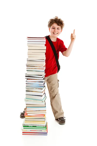 Мальчик, стоящий рядом с грудой книг — стоковое фото