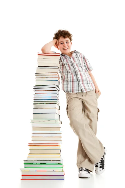 Junge steht dicht an Bücherstapel — Stockfoto