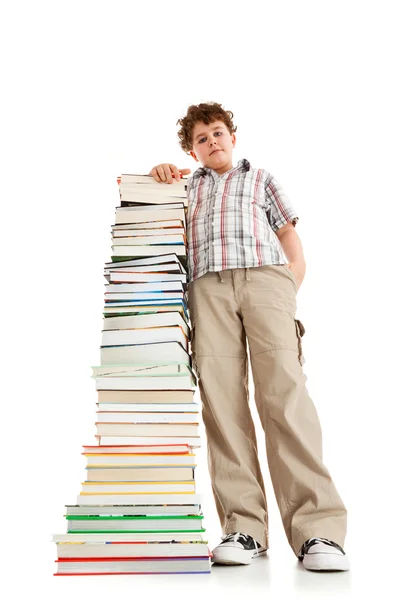 Ragazzo in piedi vicino alla pila di libri — Foto Stock