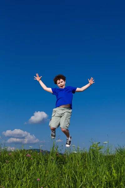 Niño saltando contra el cielo azul — Foto de Stock