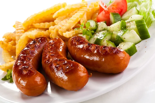 Grilled sausages with chips and vegetables — Stock Photo, Image