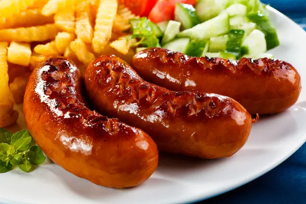 Grilled sausages with chips and vegetables — Stock Photo, Image